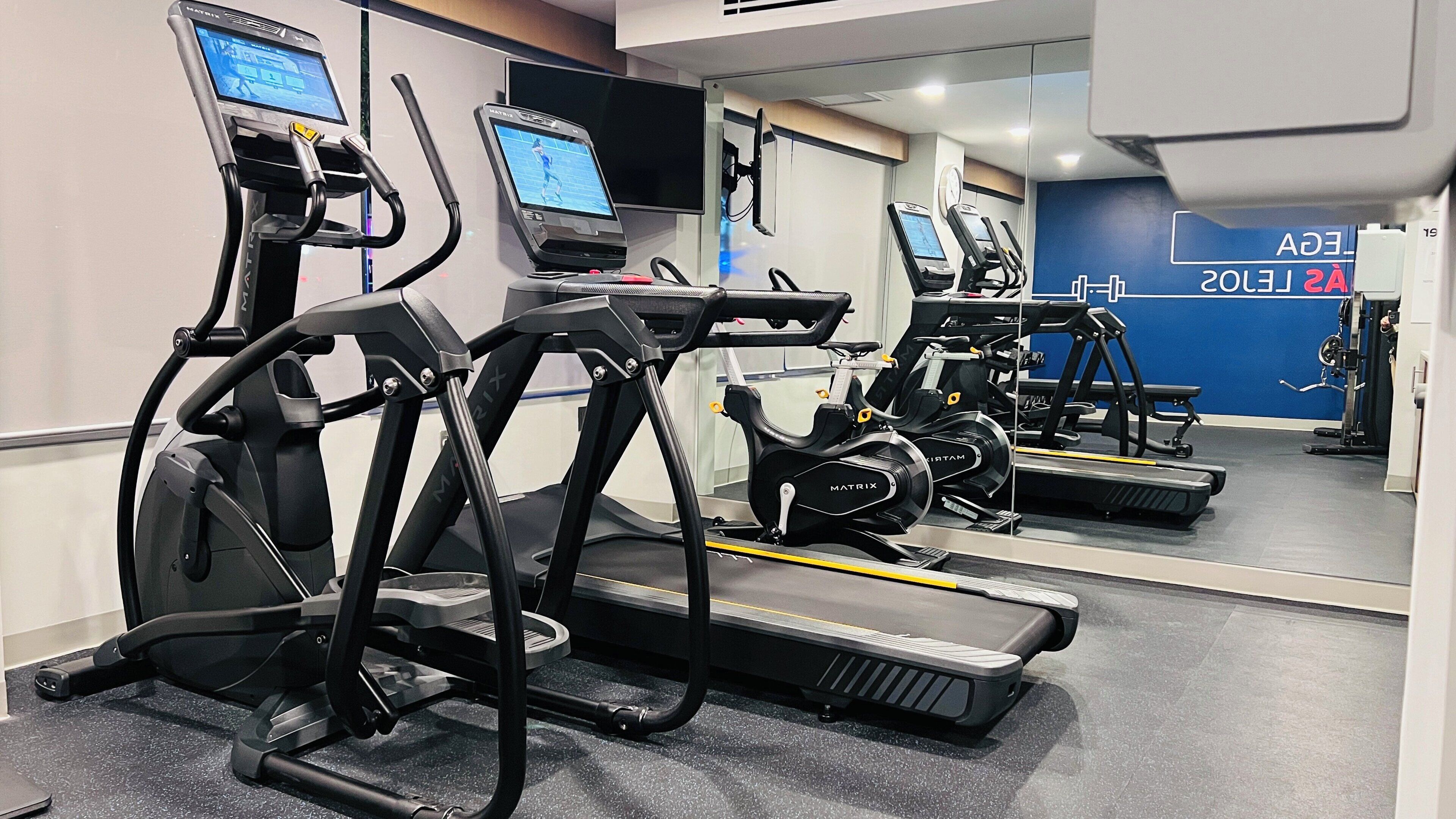 A gym with treadmills, exercise bikes, and weight machines.