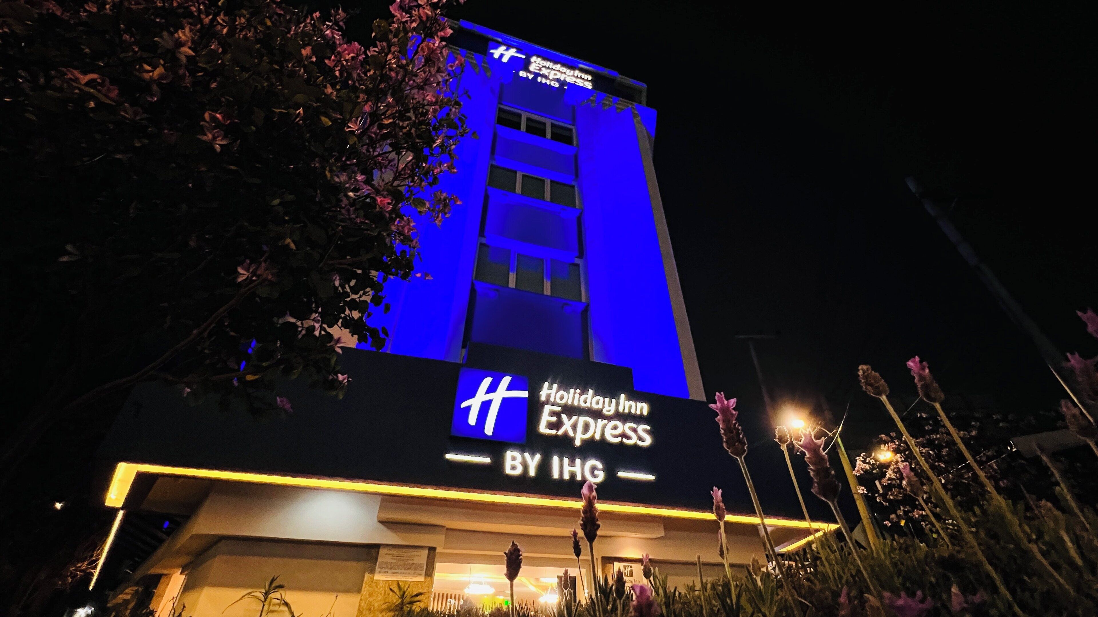 Un bâtiment de l’hôtel Holiday Inn Express, reconnaissable à son enseigne bien visible, entouré de verdure.