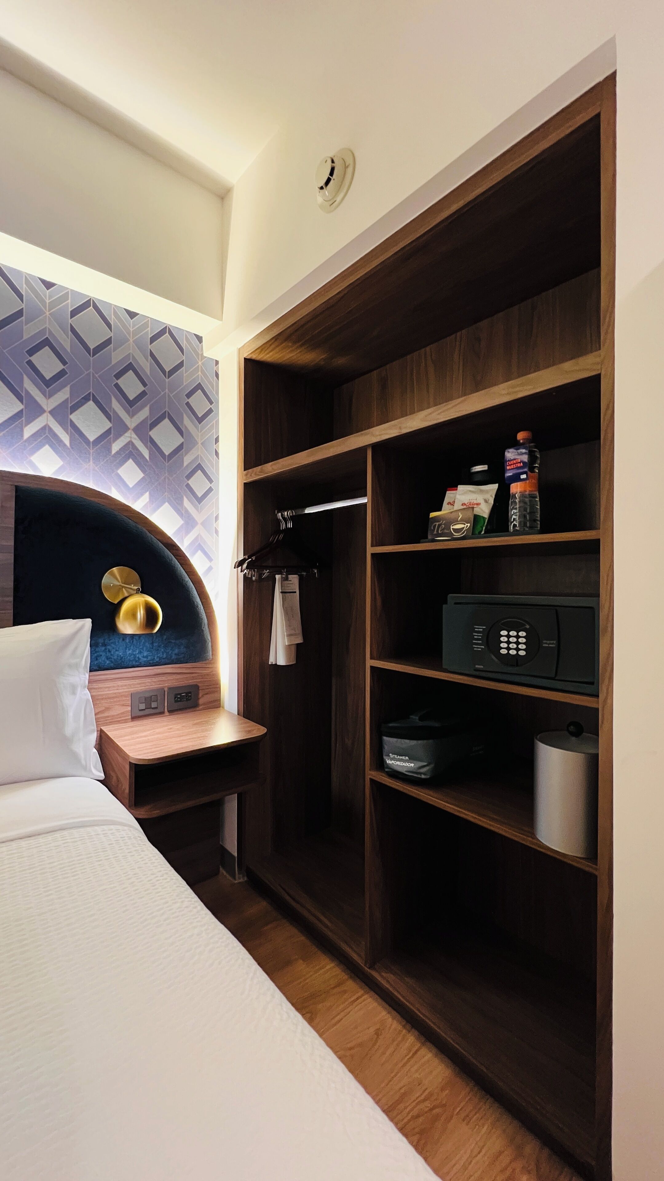 Een hotelkamer met een bed, een houten kast, een minibar en een wandradiator.