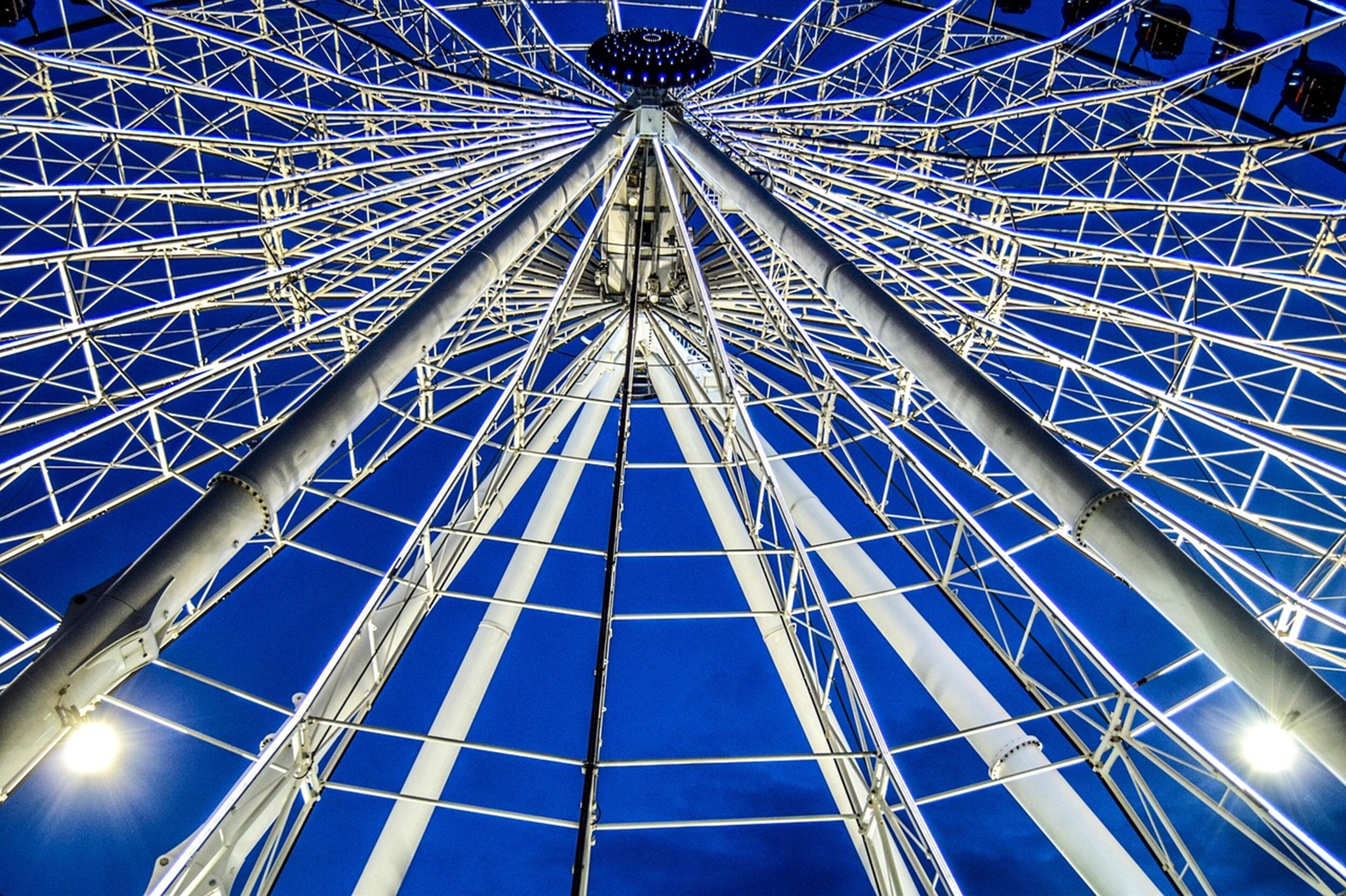 A Ferris wheel with a complex metal framework and a blue sky background.