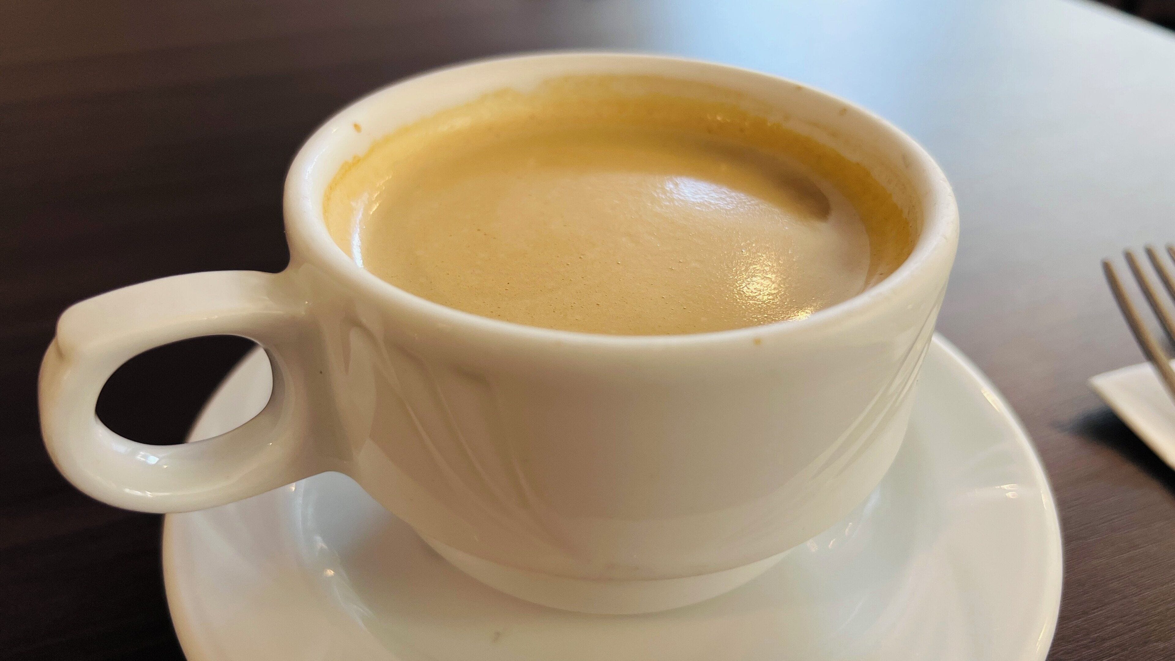 A white cup of coffee on a saucer.