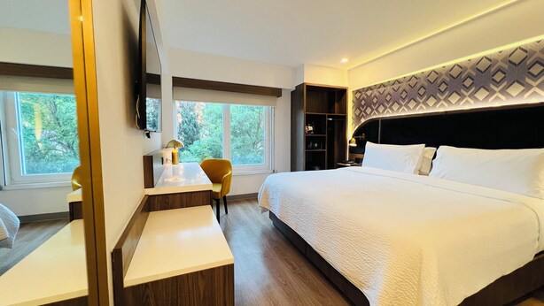 A modern hotel room with a large bed, a desk with a chair, a TV, and a view of trees through the window. - Holiday Inn Express Ciudad De Mexico Condesa by IHG (Mexico City)