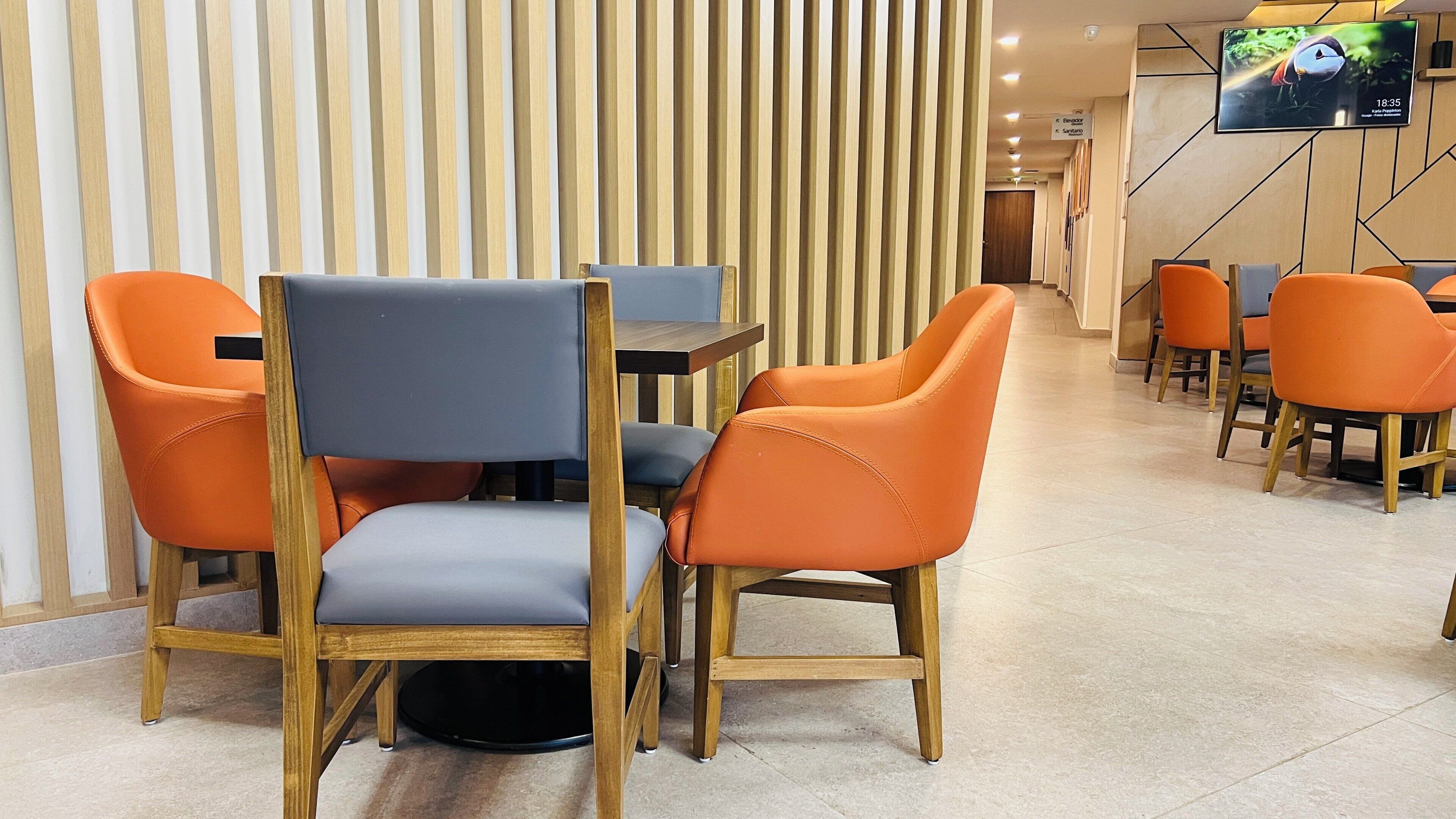 Un restaurante con sillas y mesas de madera, una pantalla de televisión y una pared a rayas.