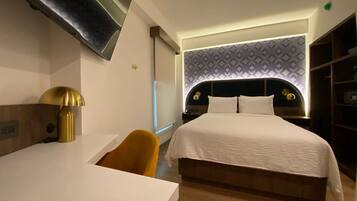 Una habitación de hotel moderna con una cama, un escritorio, una silla y un televisor montado en la pared.