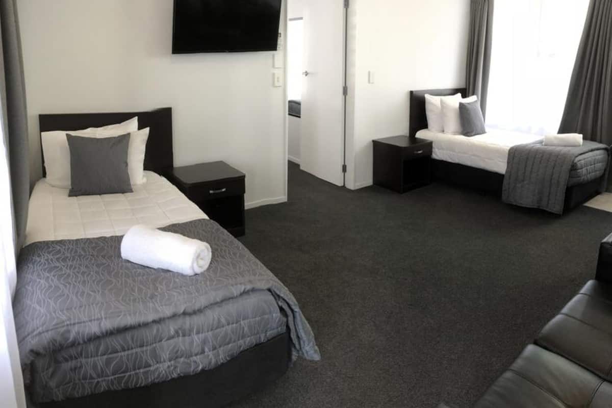 Habitación de hotel con dos camas, un televisor de pantalla plana, un escritorio pequeño y un sofá.