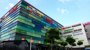 A multi-story building with a glass facade, prominently displaying the name 'Grand Mall'.