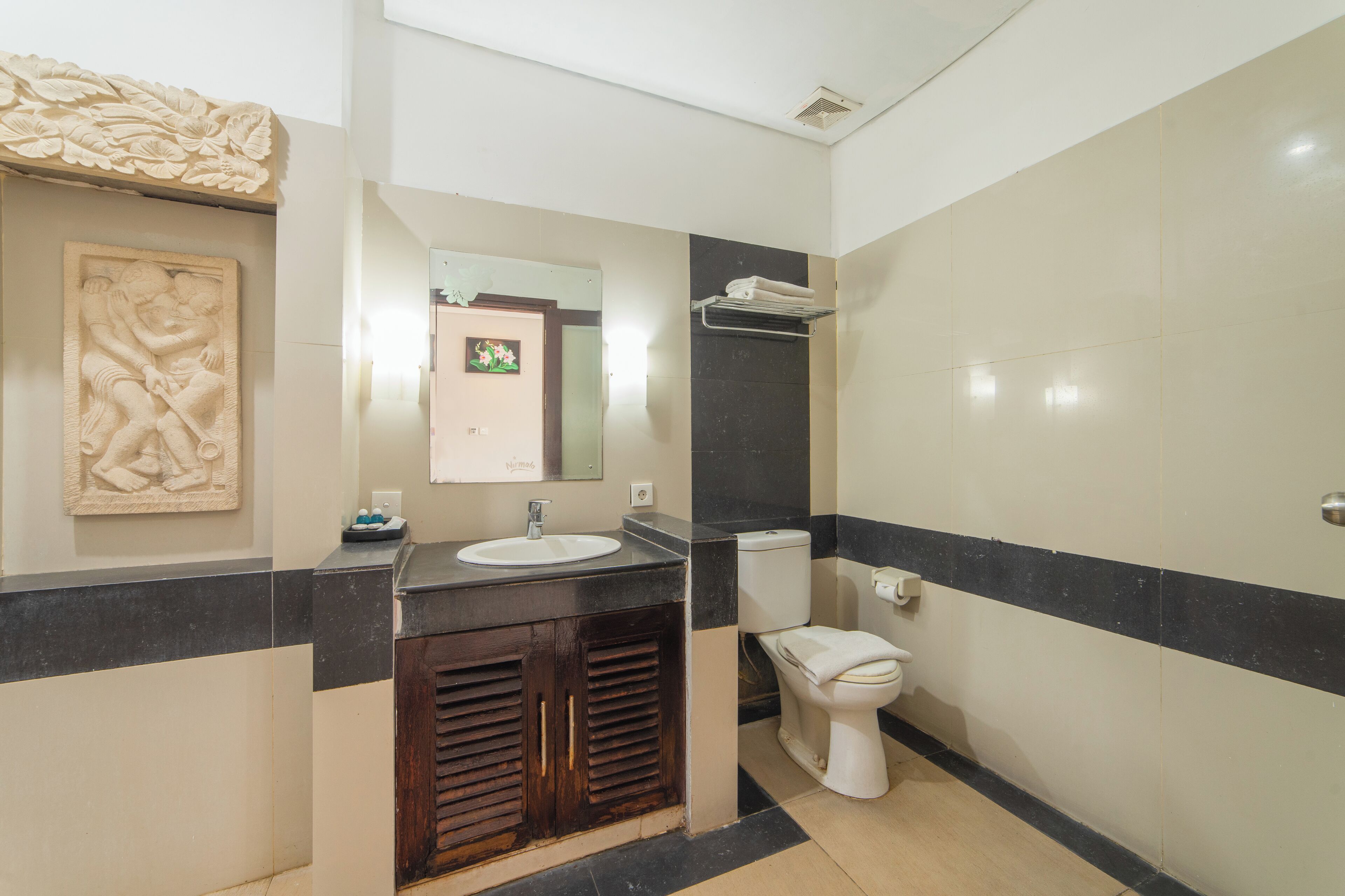 A bathroom with a sink, toilet, and decorative wall art.
