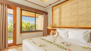A hotel room with a bed, a view of greenery, and a large window. - Nirmala Heritage Hotel (Jimbaran)