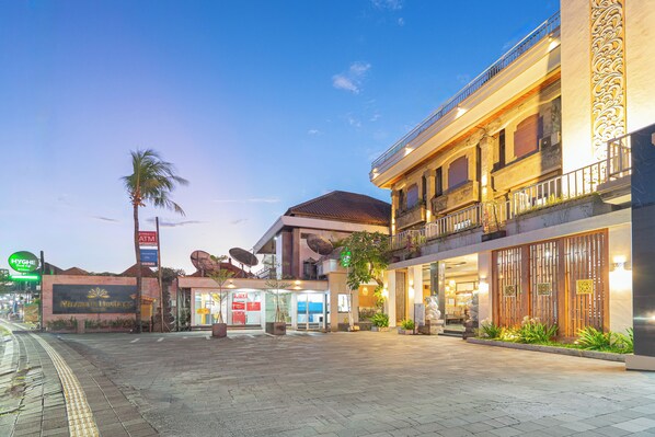 A hotel with a central courtyard, a palm tree, and a sign for 'Nirmala Heritage.' - Nirmala Heritage Hotel (Jimbaran)