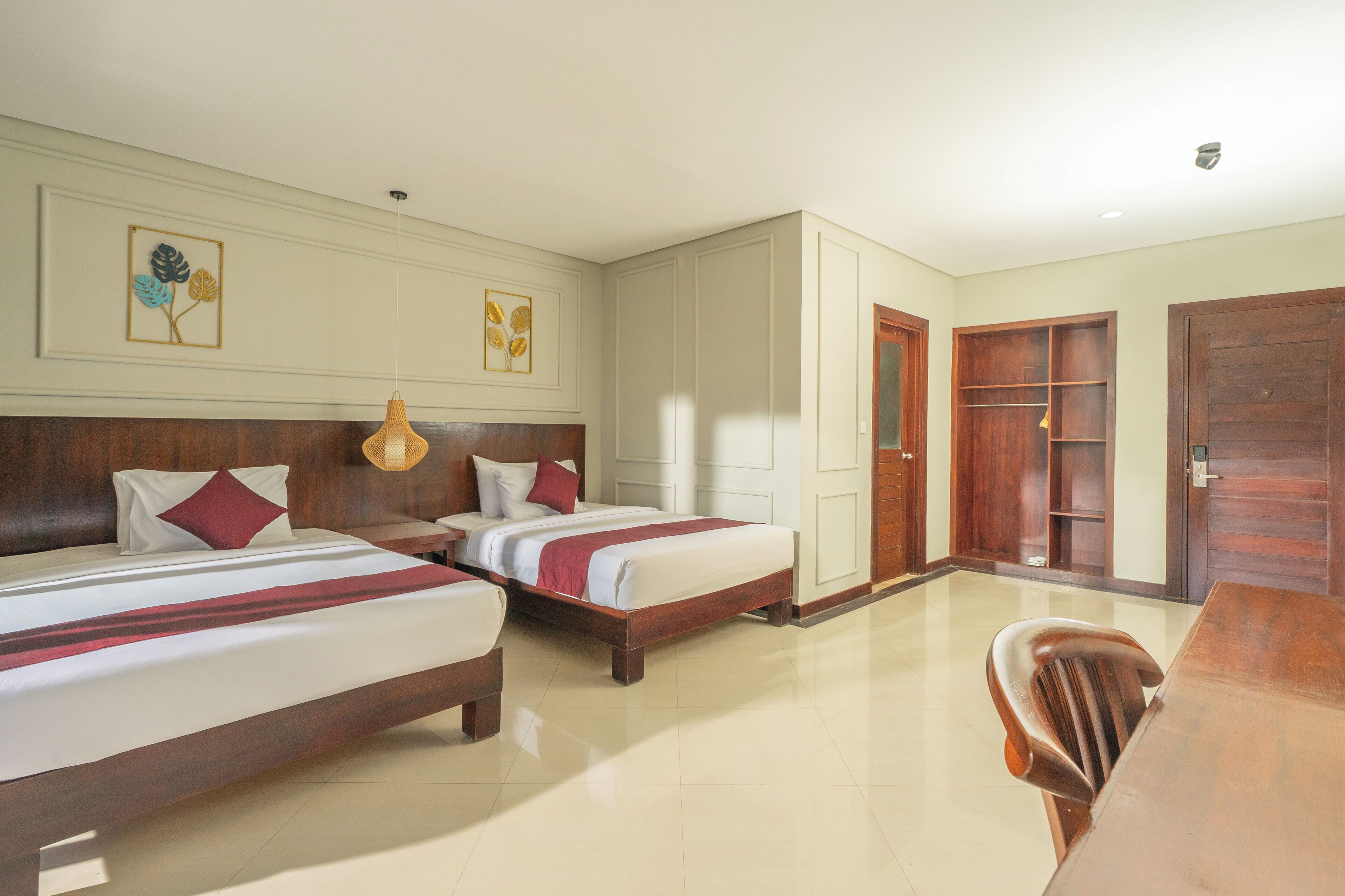 A hotel room with two beds, a wooden headboard, a dining table, and a chair.