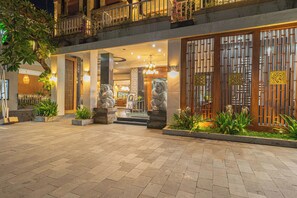 A hotel entrance with a tiled courtyard, stone statues, and a traditional wooden gate. - Nirmala Heritage Hotel (Jimbaran)