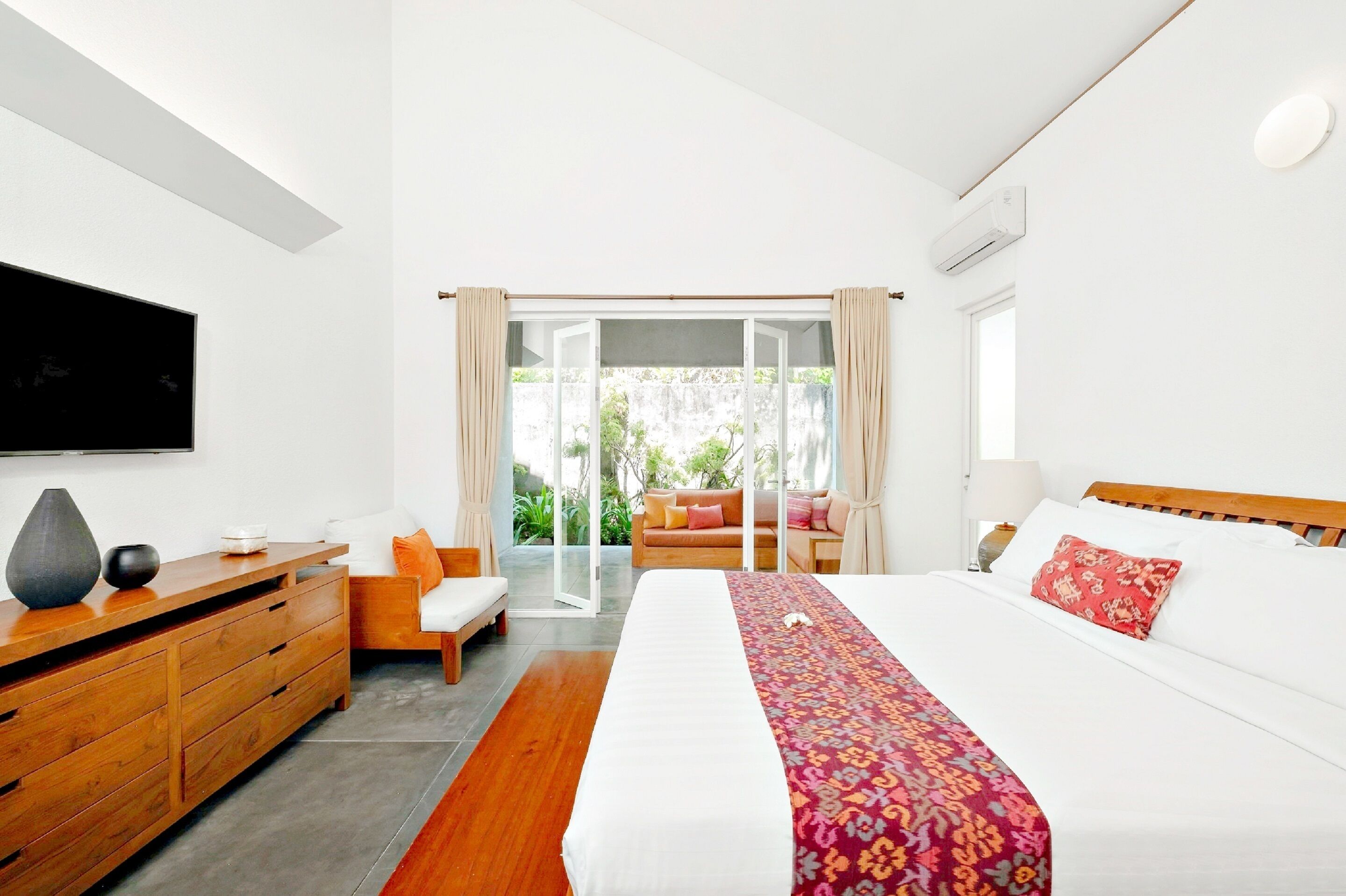Una habitación de hotel moderna con una cama grande, muebles de madera, un televisor de pantalla plana y vistas al exterior.