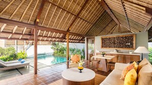A spacious indoor area with a pool, a round wooden coffee table, and a seating area with cushions. - Mayaloka Villas Seminyak (Keroboken Kelod)