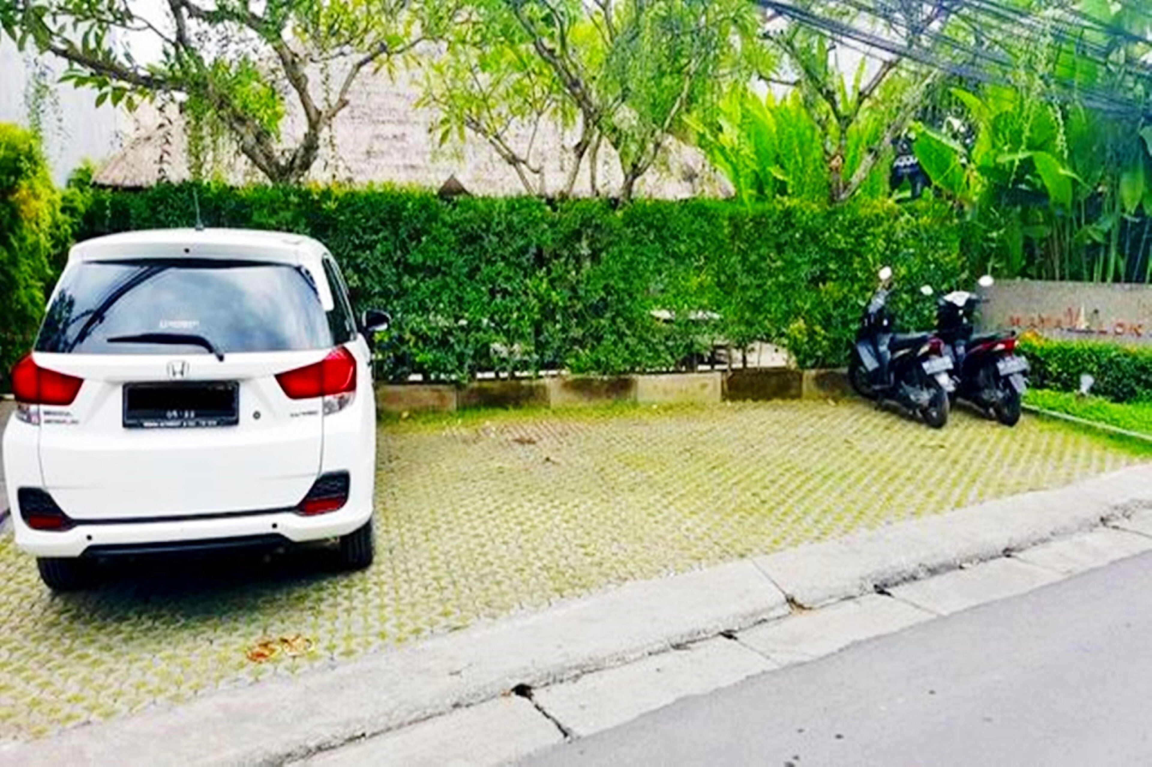 A white car parked on a paved area with a motorcycle nearby.