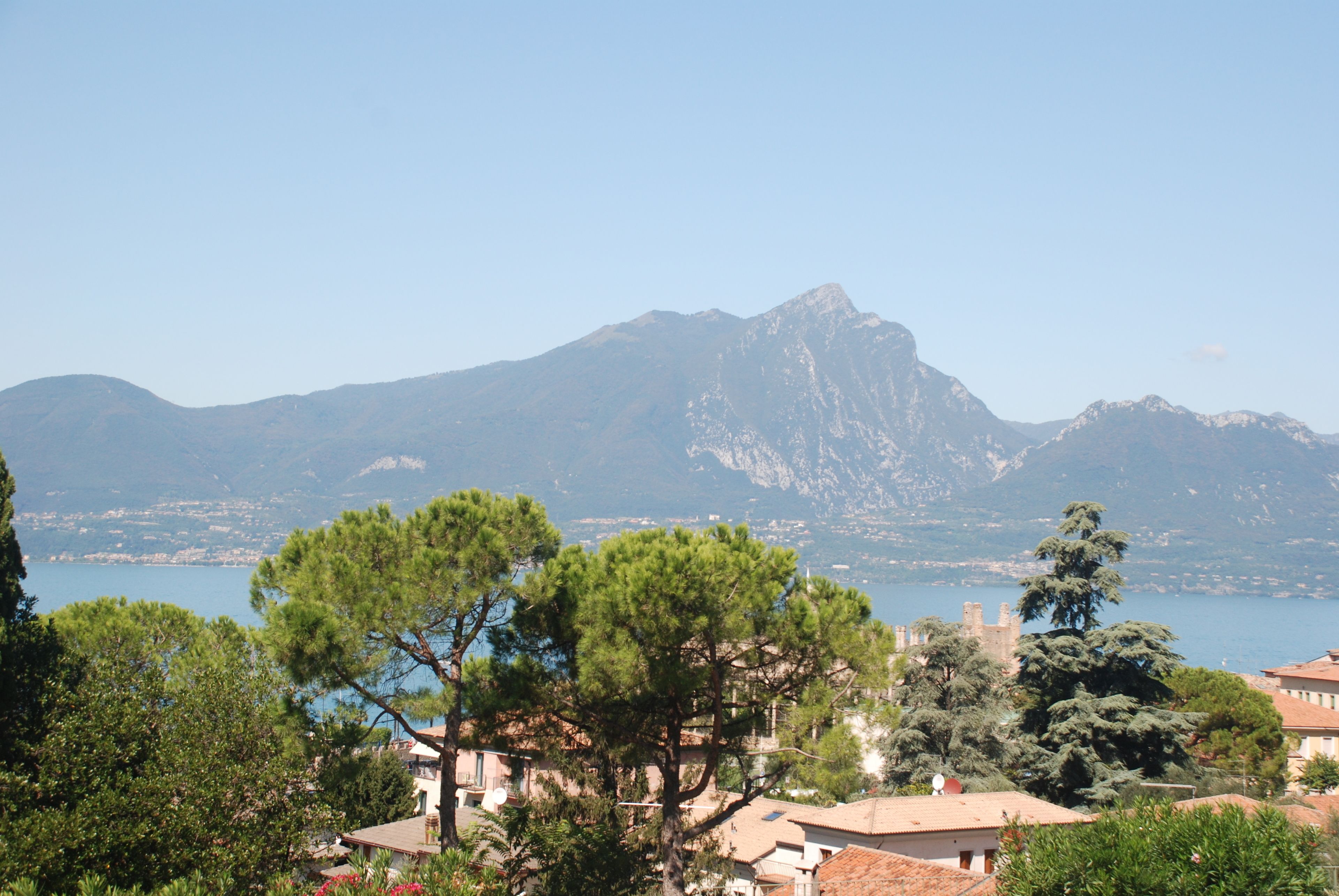 A coastal town with a prominent mountain in the background, surrounded by lush greenery and a clear blue lake.