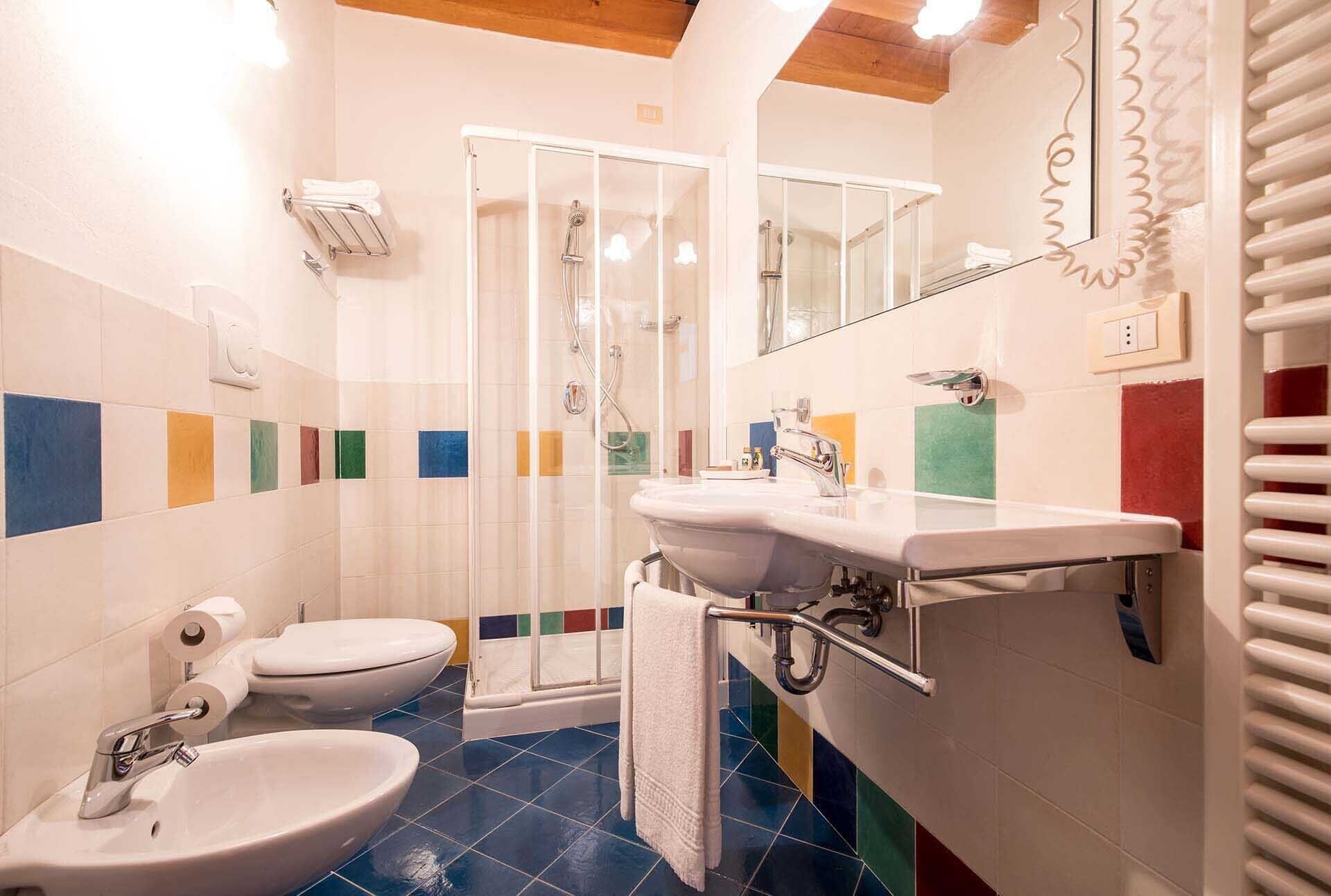 Un baño con ducha, inodoro, lavabo y toallero.