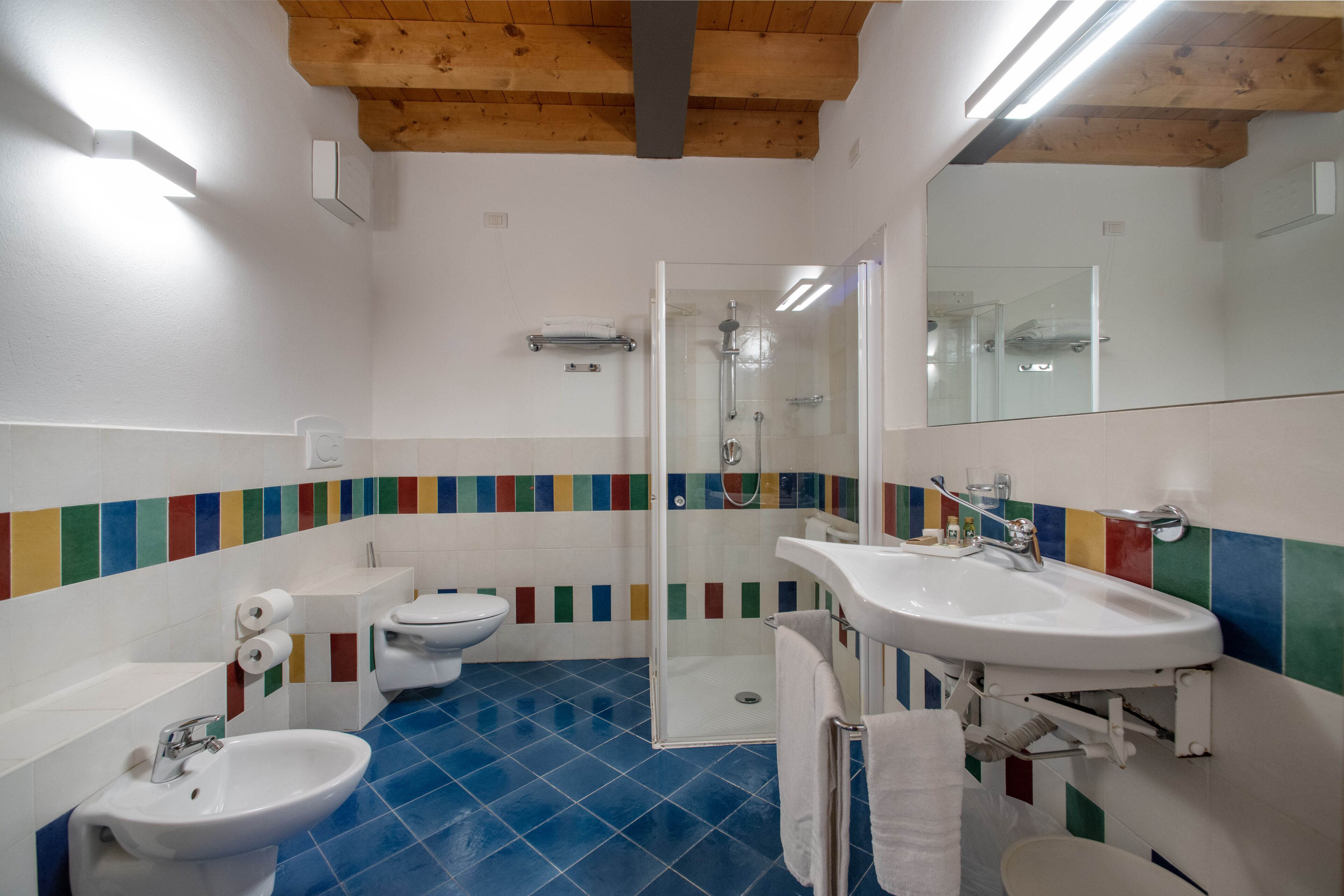 A bathroom with a shower, toilet, bidet, and sink.