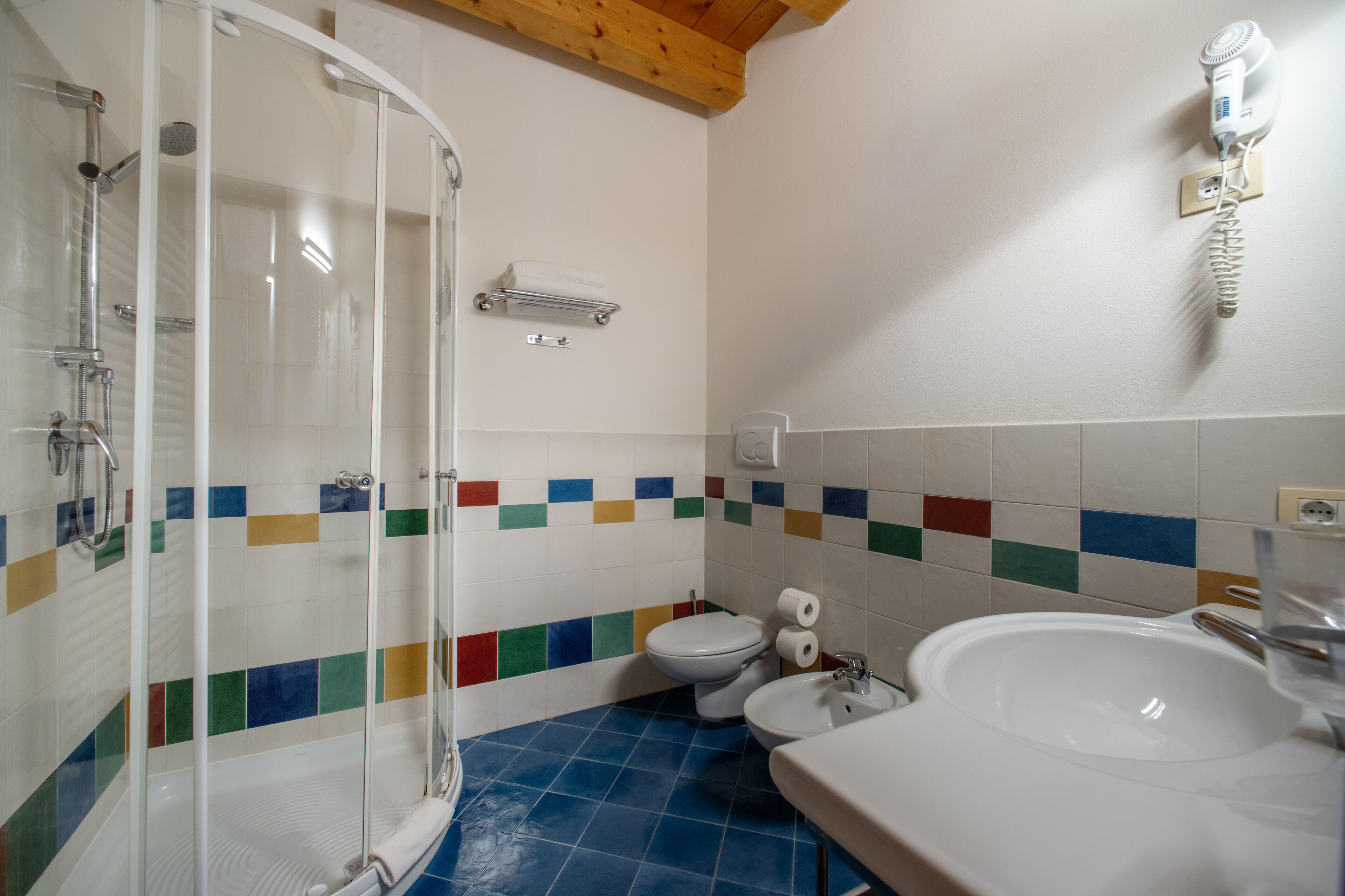A bathroom with a glass shower enclosure, a toilet, a bidet, and a sink.