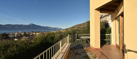 A balcony with a view of a coastal town and mountains.