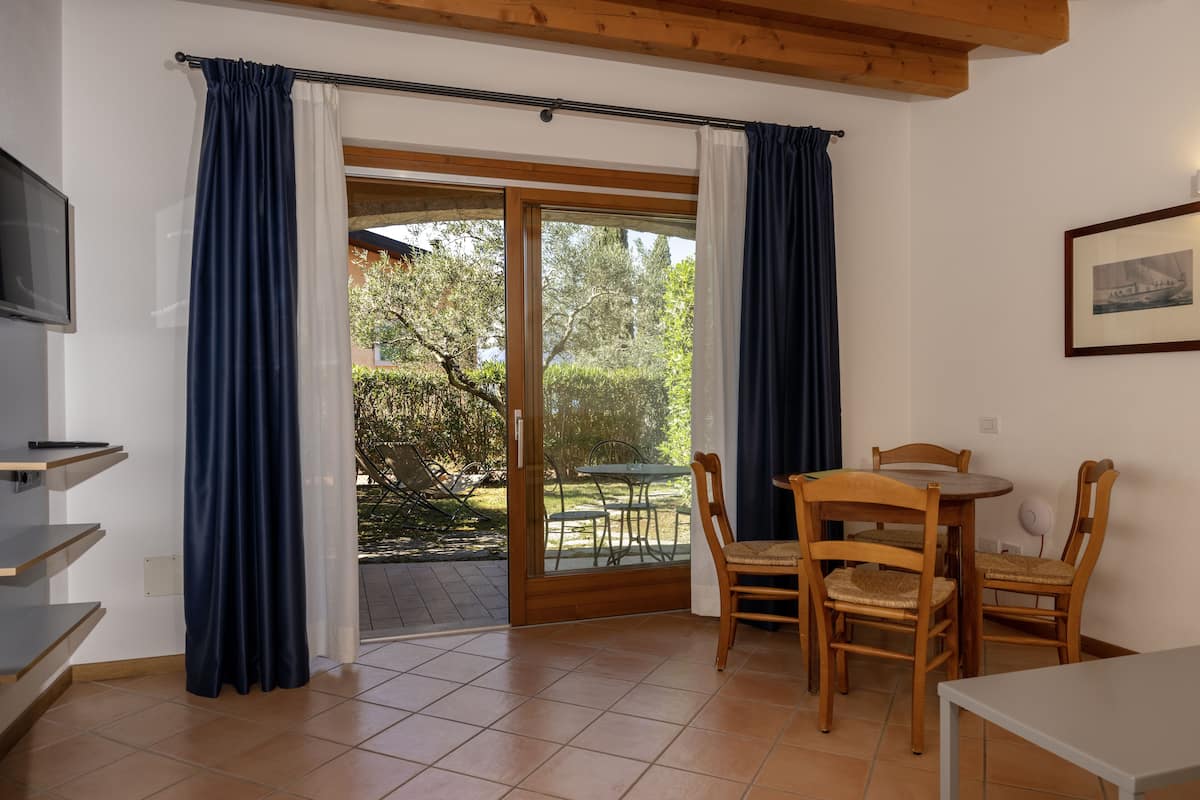A room with a sliding glass door leading to an outdoor area, wooden furniture, and a framed picture on the wall.
