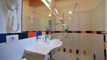 A bathroom with a white sink, a glass shower enclosure, and a mirror above the sink.