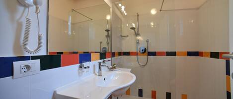 A bathroom with a white sink, a glass shower enclosure, and a mirror above the sink.