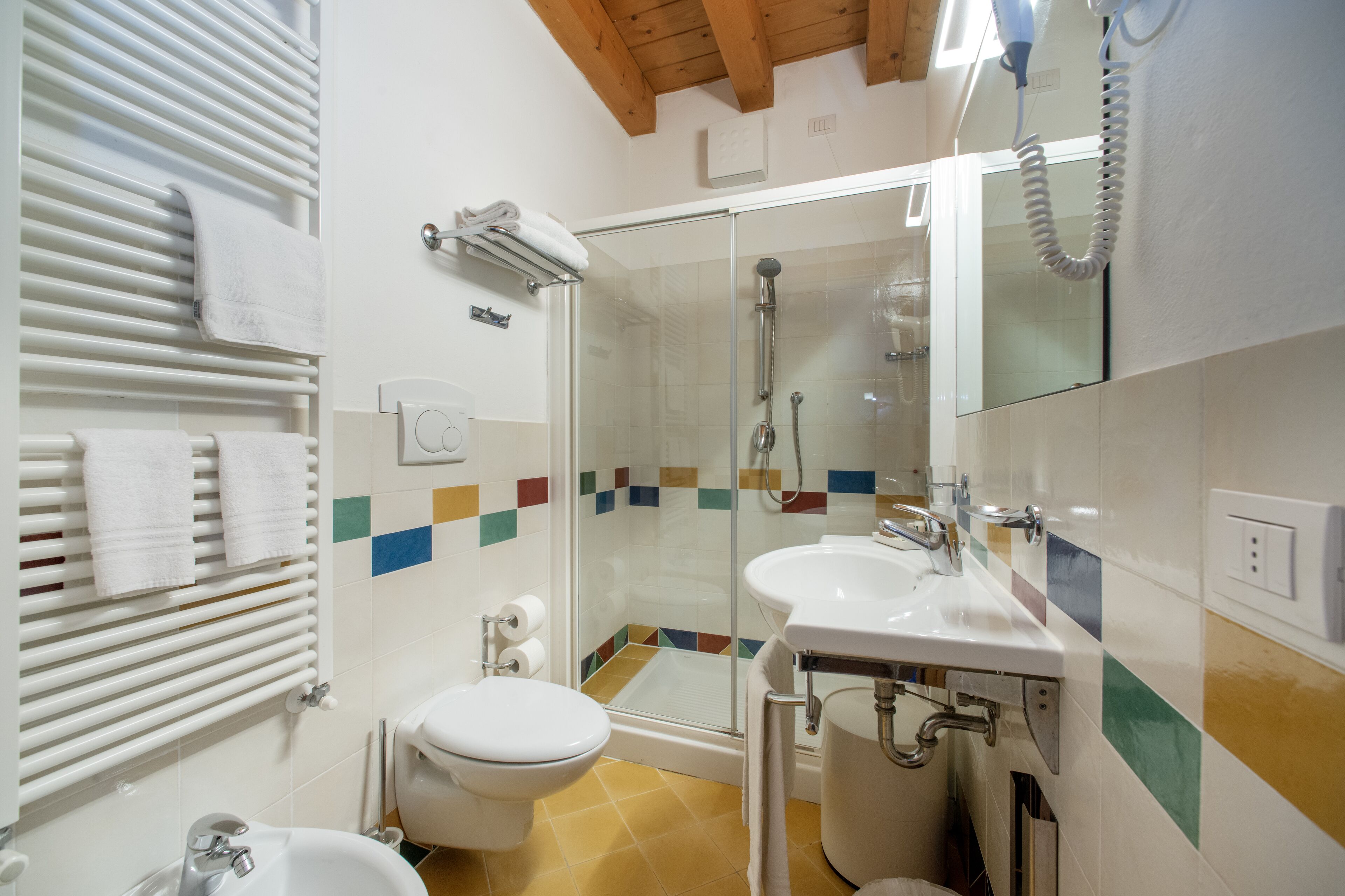A bathroom with a glass shower enclosure, a white sink, and a toilet.