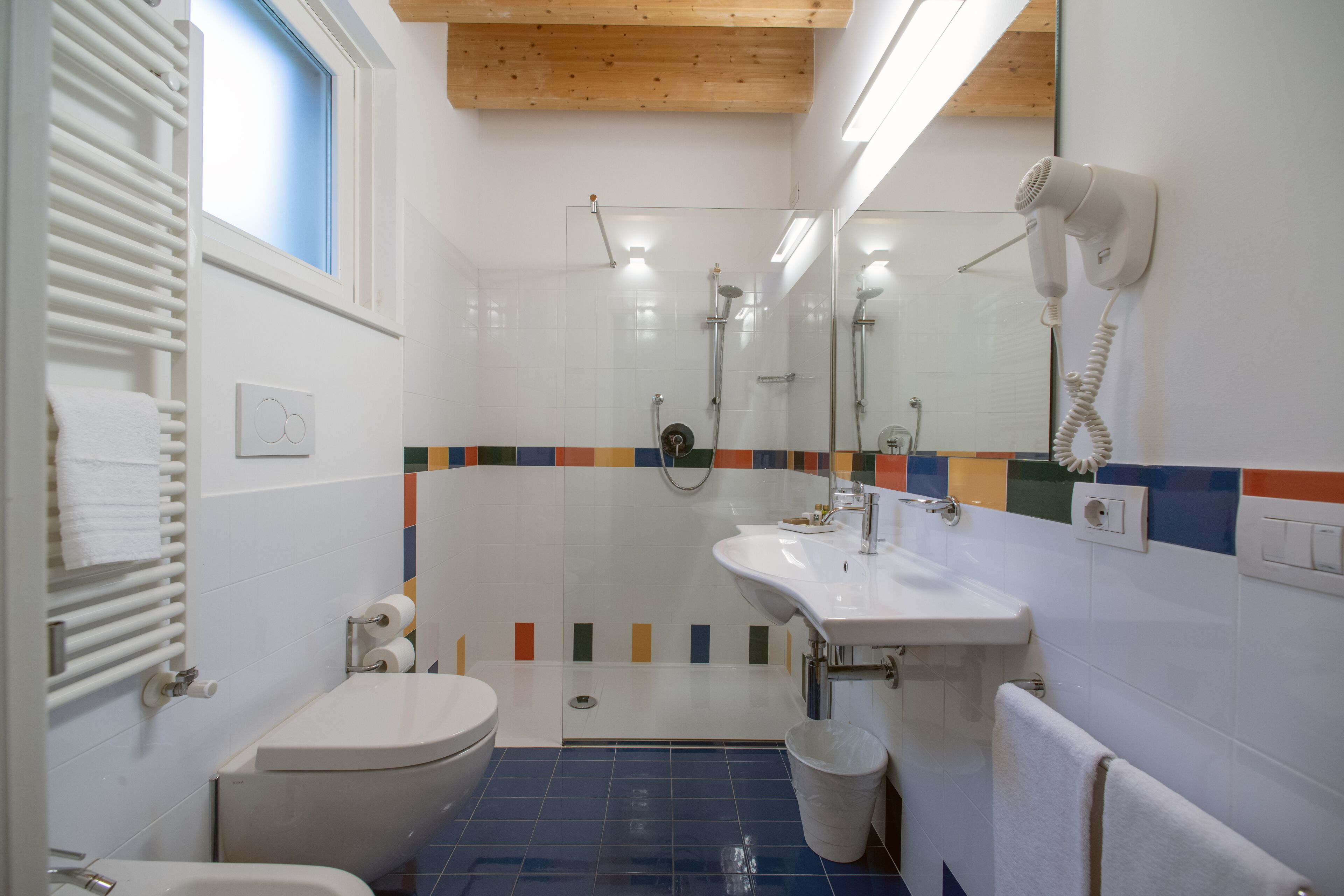 Une salle de bain équipée d’une douche, de toilettes, d’un lavabo et d’un sèche-cheveux fixé au mur.