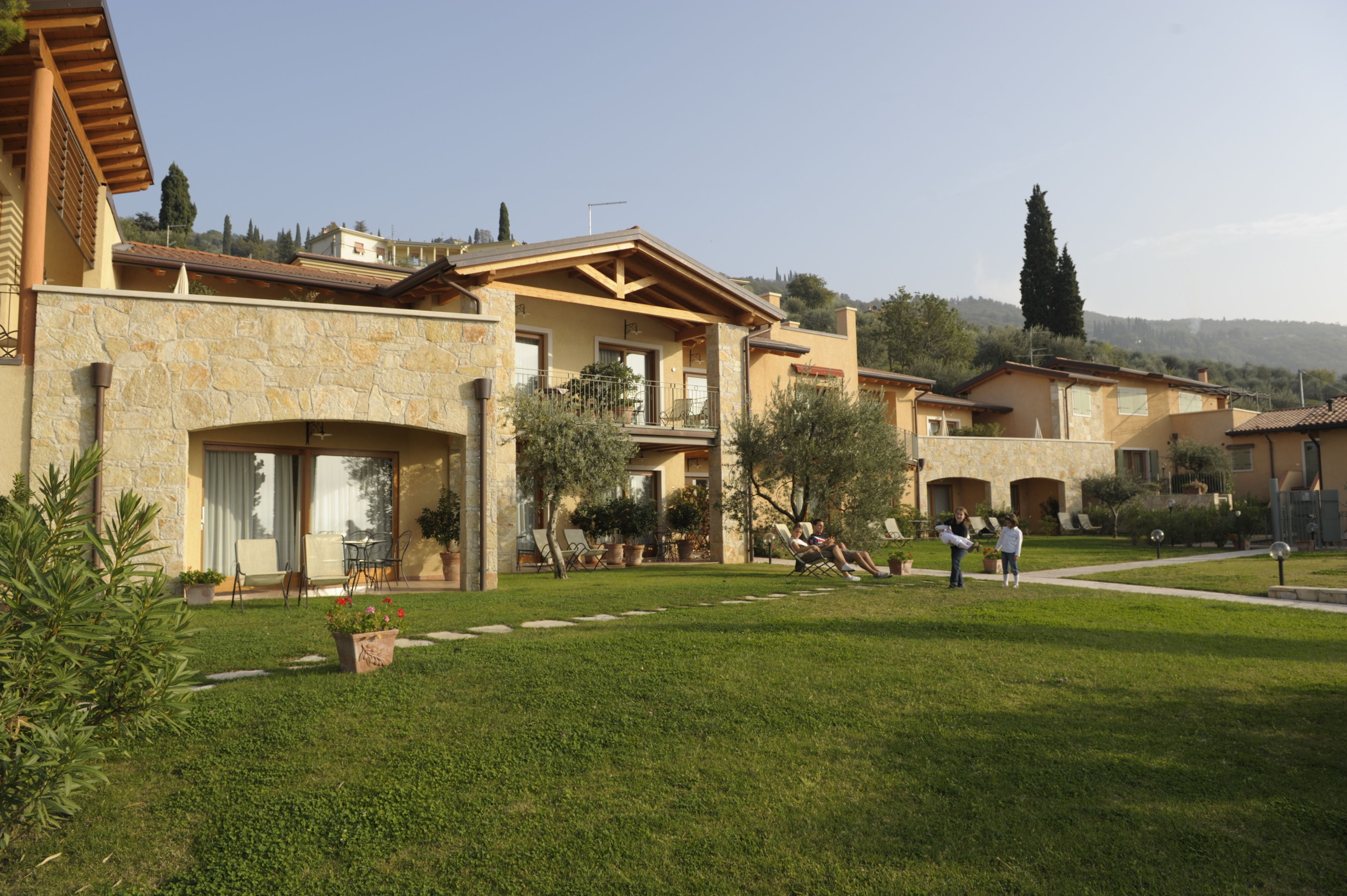 A residential building with stone walls, a balcony, and a well-maintained lawn.