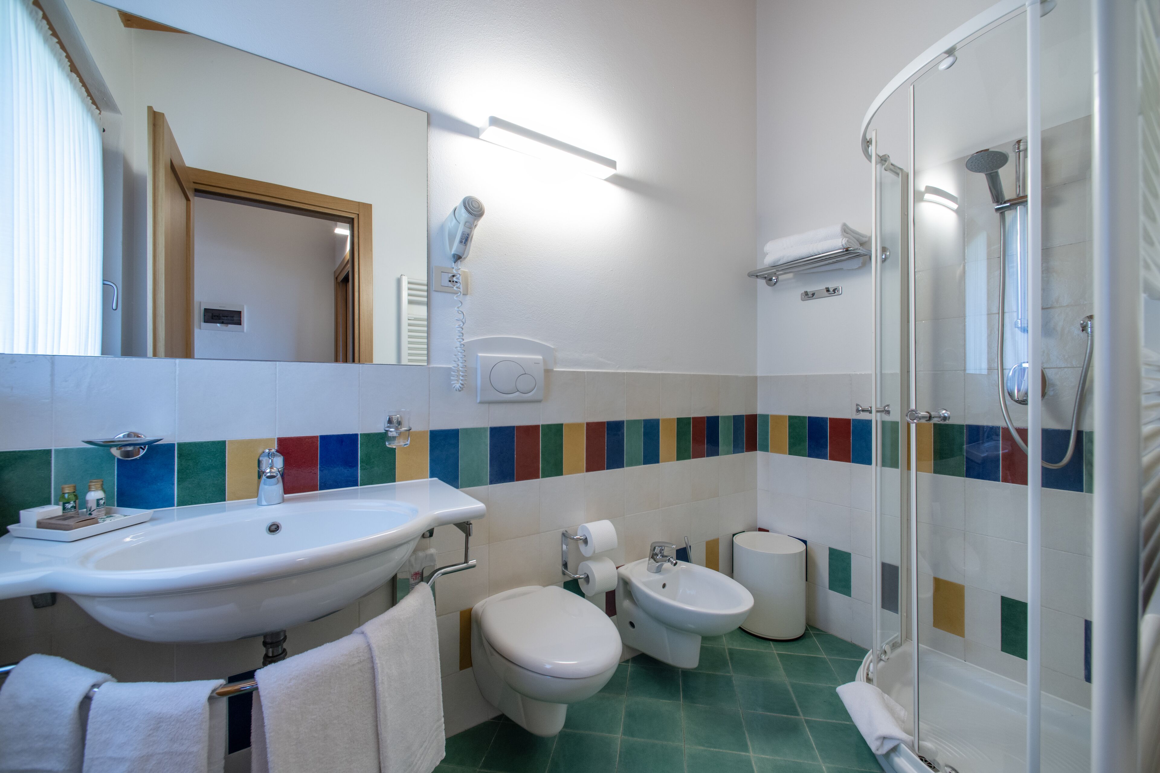 A bathroom with a sink, toilet, bidet, and a glass-enclosed shower.