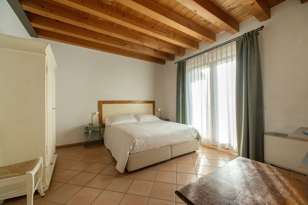 A bedroom with a bed, a bedside table, a nightstand, and a wardrobe.