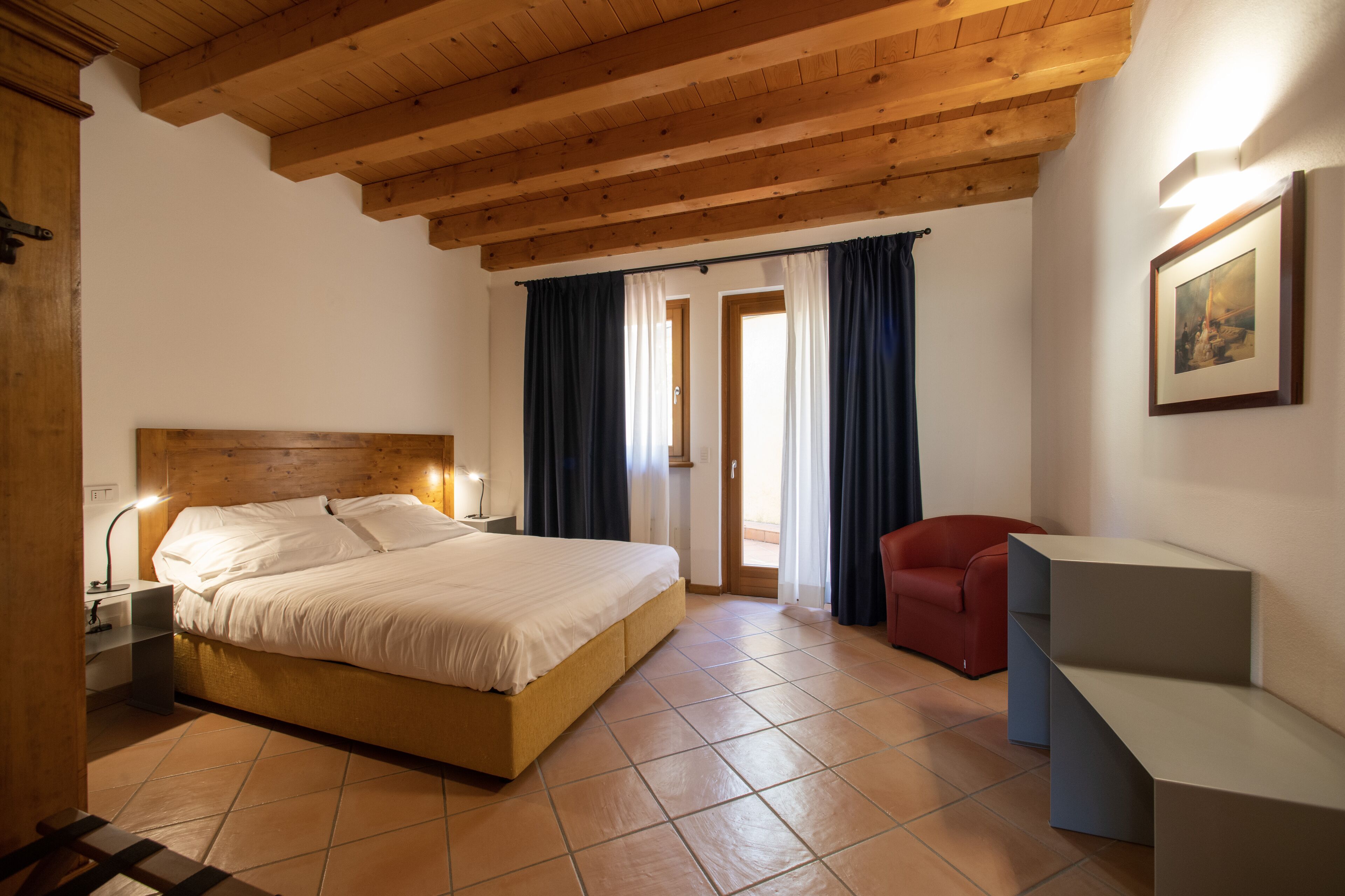 A bedroom with a wooden ceiling, a bed, a desk, and a chair.