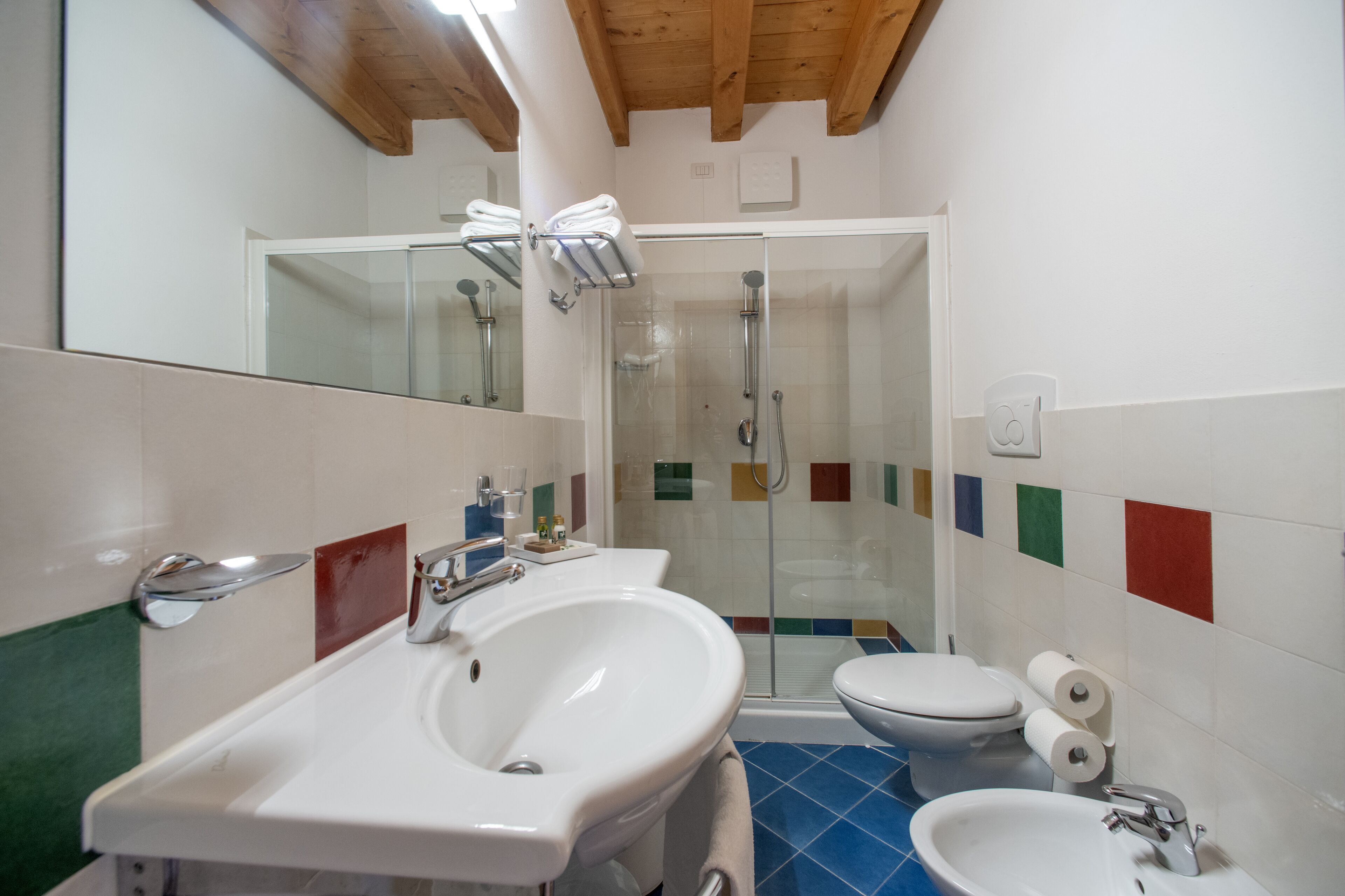 A bathroom with a white sink, a toilet, and a glass shower enclosure.