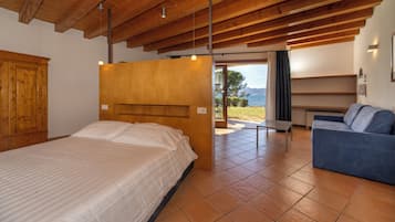 Un dormitorio con techo de madera, cama, sofá y vistas al exterior.