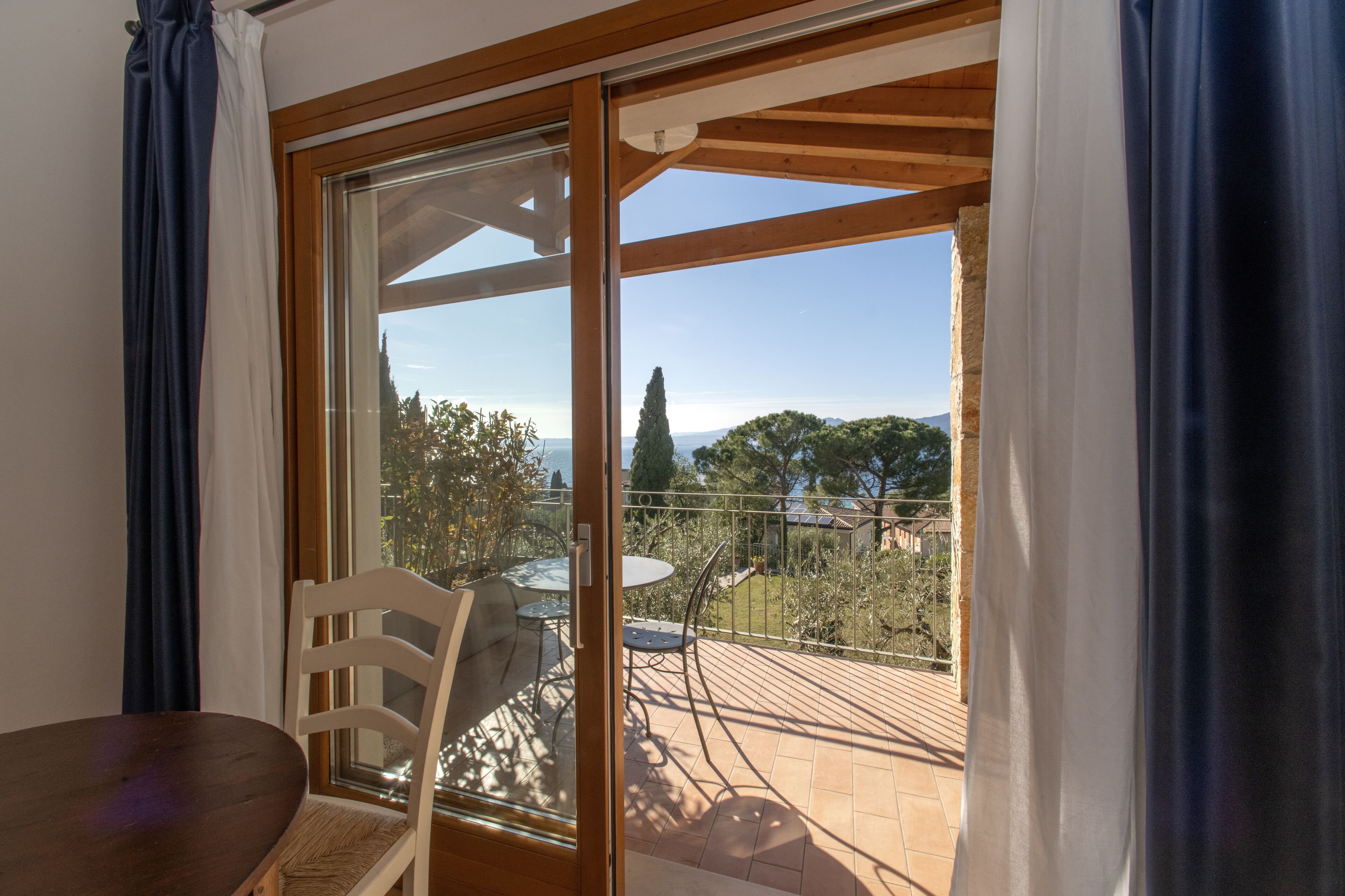 Un balcone con tavolo e sedie, vista su un paesaggio verde e colline lontane.