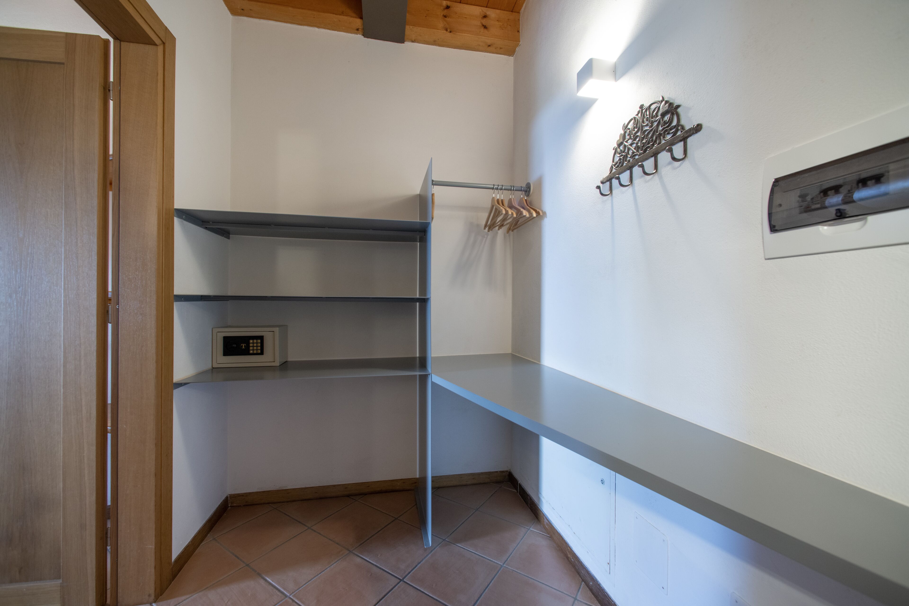 Ein Eckzimmer mit Holztür, einem Metallregal, einem fest montierten Heizkörper und einem Handtuchhalter.