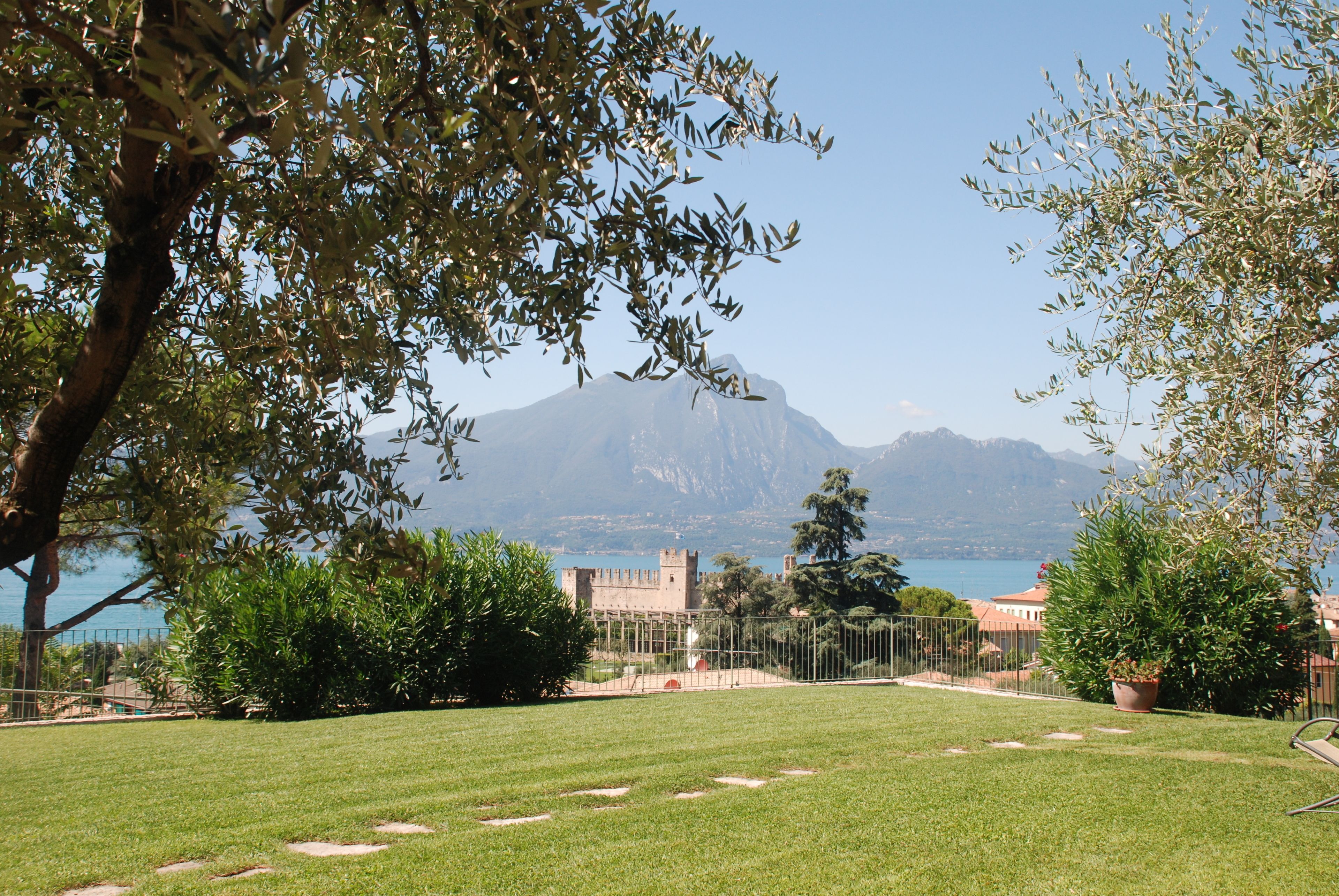 A grassy lawn with a view of a castle and mountains in the background.