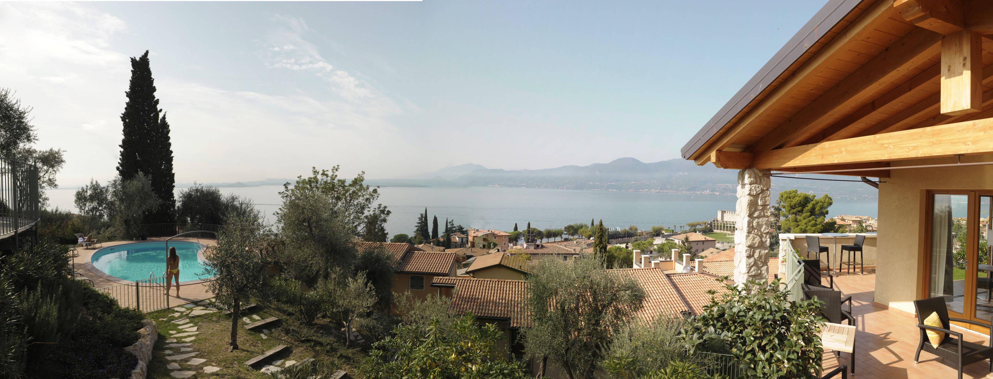 A pool with a view of the sea, surrounded by trees and buildings.