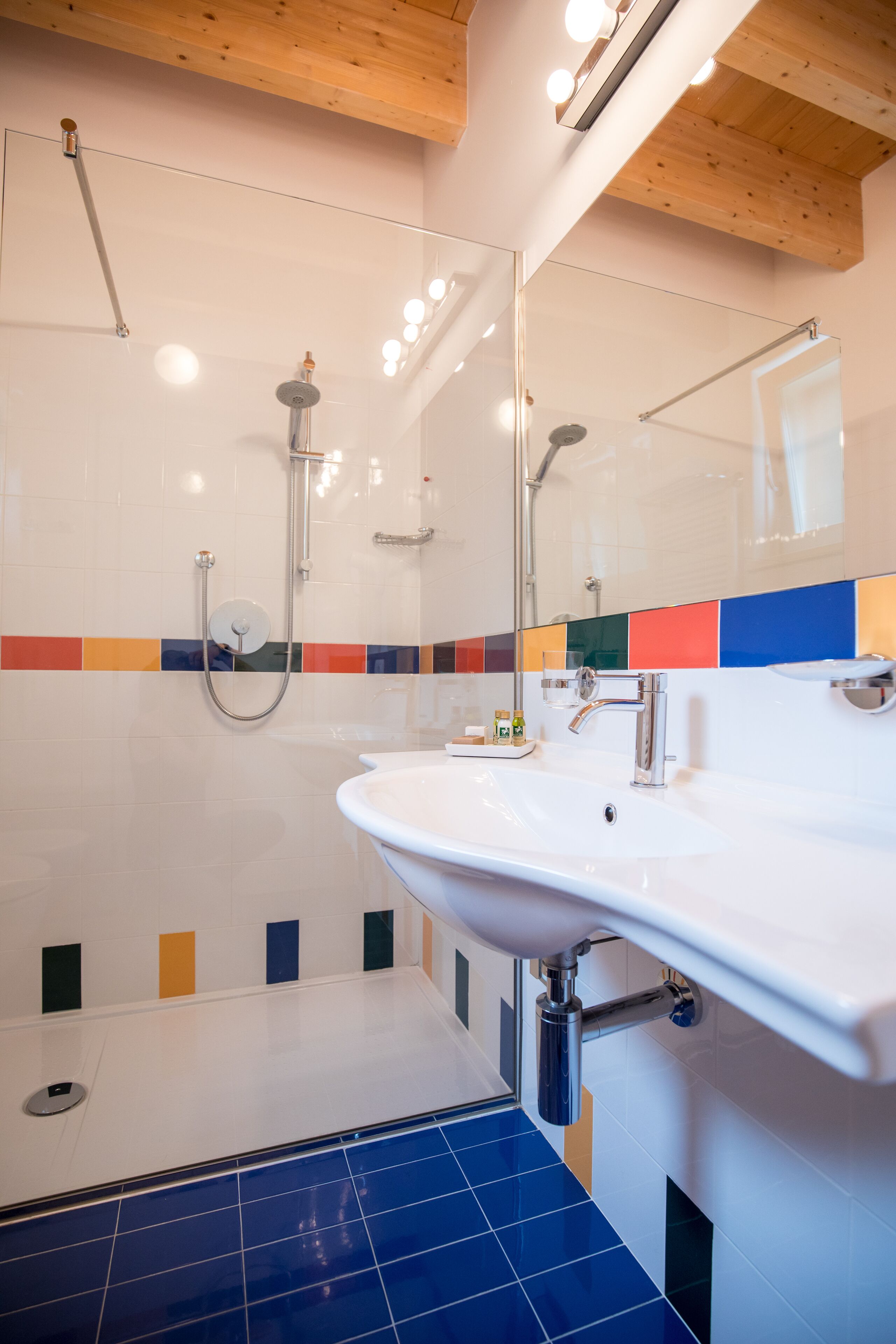 A modern bathroom with a glass shower enclosure, a white sink, and a tiled floor.