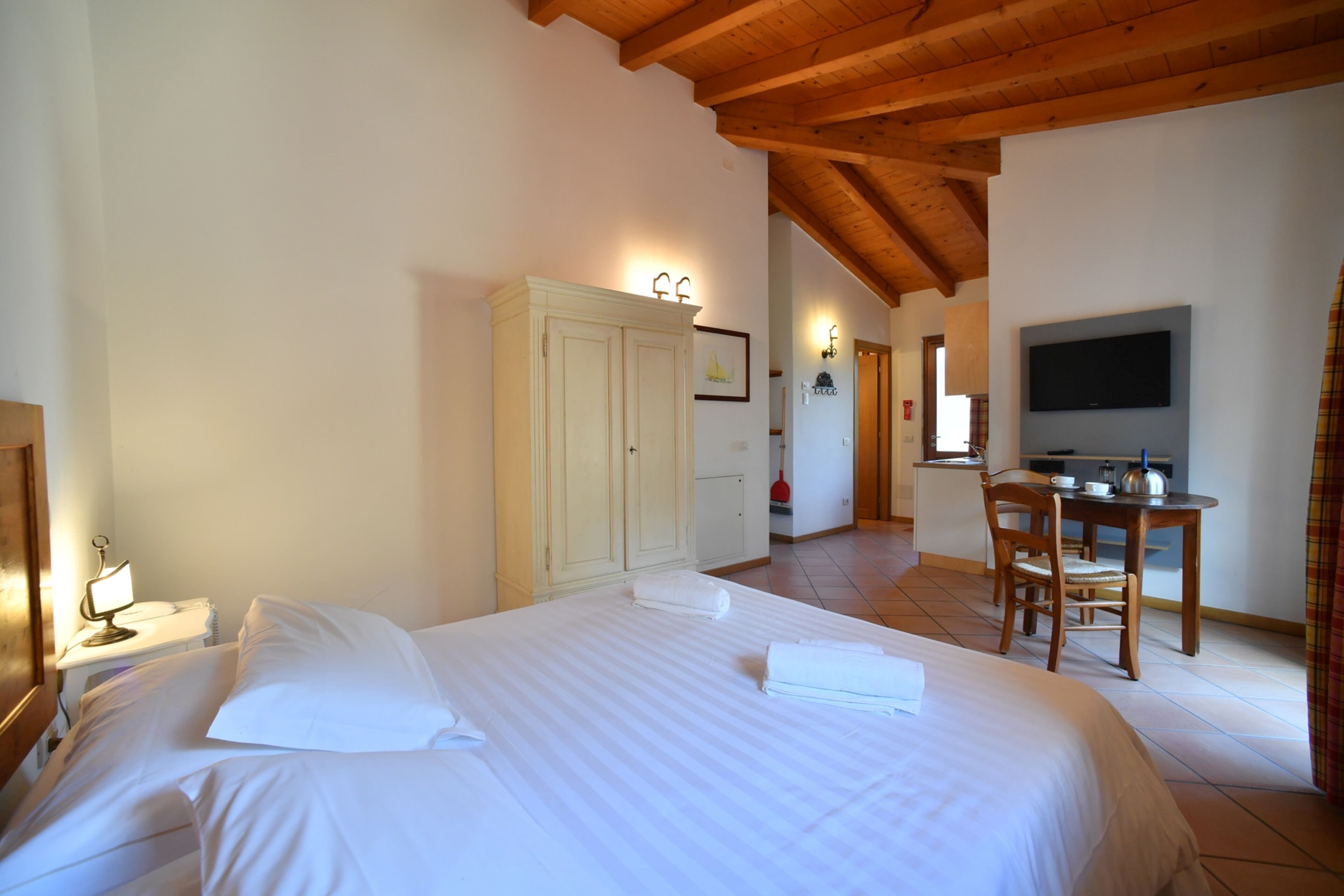 Una habitación de hotel con cama, escritorio, televisión y armario.