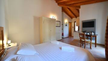 Una habitación de hotel con cama, escritorio, televisión y armario.