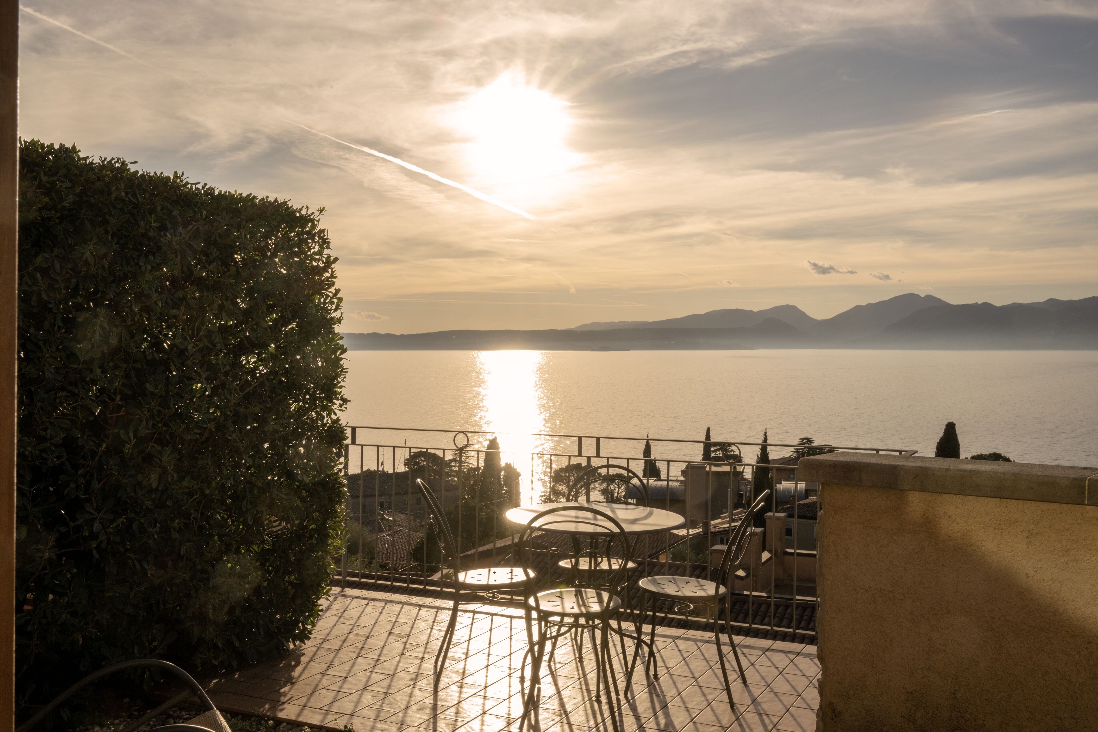 Eine Terrasse mit Blick auf das Meer und die Berge, ausgestattet mit Sitzgelegenheiten und einem Geländer.