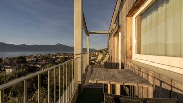 A balcony with a view of a coastal town and mountains.