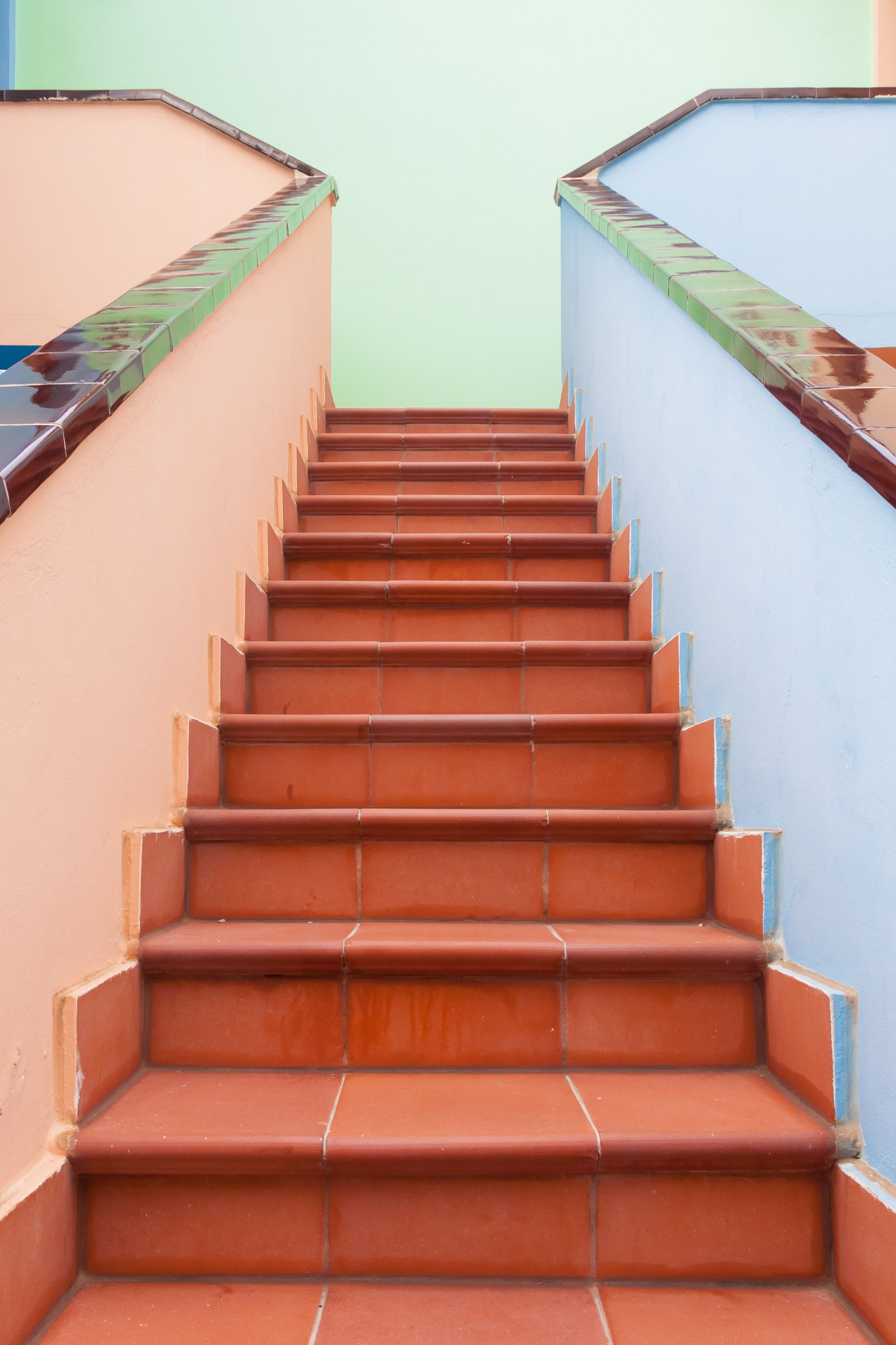 A set of red-tiled stairs leading upwards, flanked by walls in two different colors.