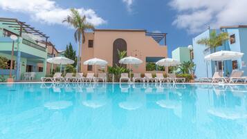 Alberca al aire libre, sombrillas en la alberca y camastros