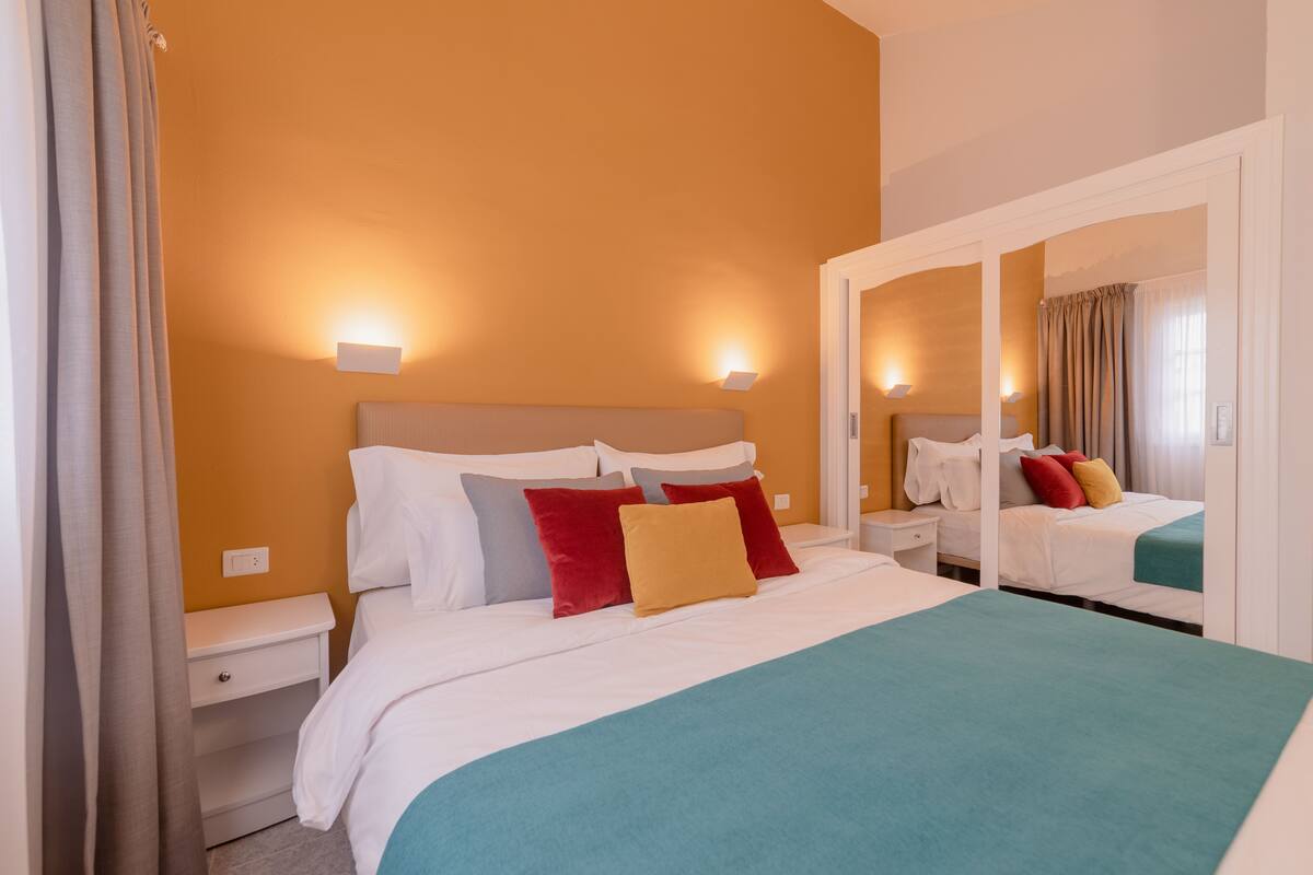 Ein Hotelzimmer mit einem großen Bett, zwei Nachttischen und einem Spiegel.