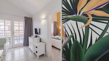A hotel room with a balcony, a TV, a desk, and a bed.