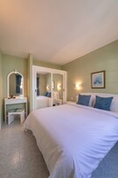 A bedroom with a large bed, a bedside table, a mirror, and a wall-mounted light fixture.