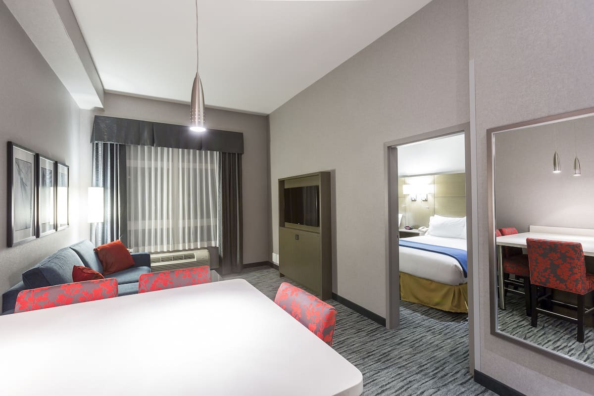 Une chambre d’hôtel avec un grand lit, un bureau, une chaise, un canapé et un téléviseur.