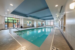 Una amplia piscina interior con agua cristalina y paredes de azulejos, bajo un techo con iluminación empotrada.